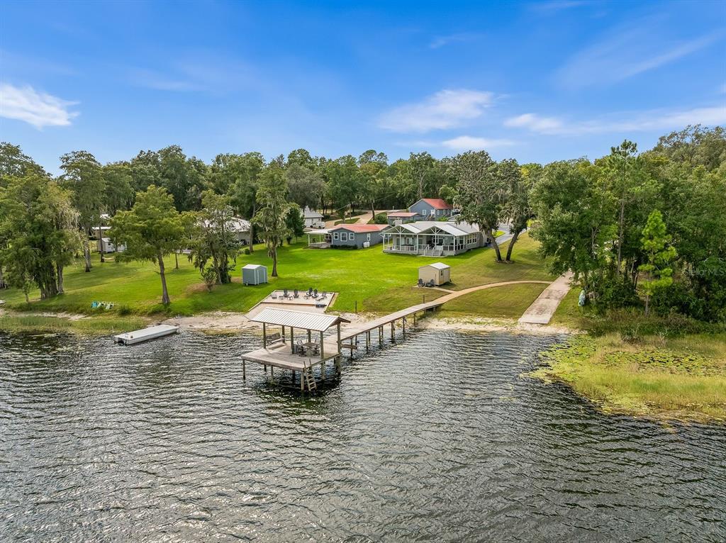 An aerial view of a lakefront property featuring a long wooden dock and several houses — 8449 LILLY LAKE ROAD, MELROSE, FL