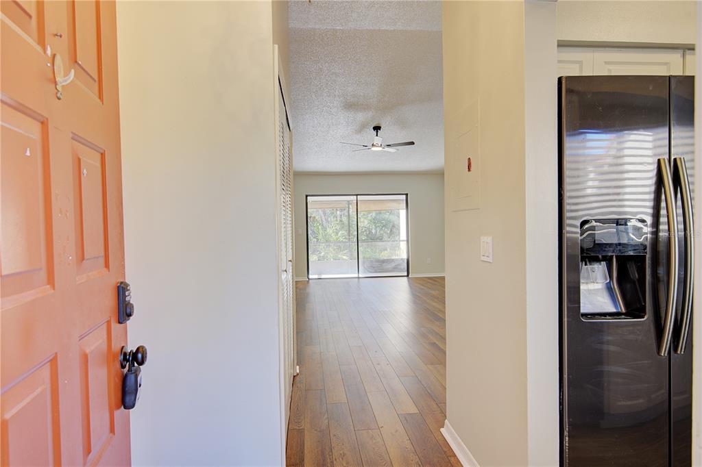 An entryway with a wood-look floor leads to a living area with a sliding glass door — 506 CLUB DRIVE, WINTER SPRINGS, FL