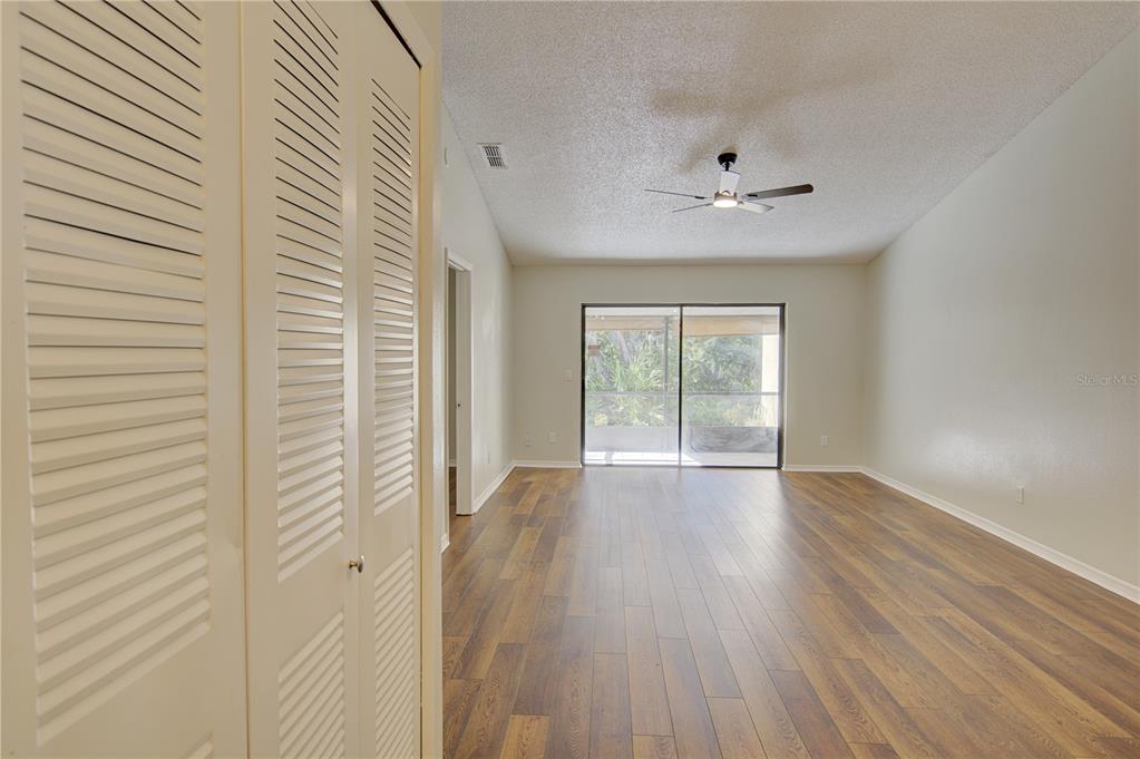 An empty room features wood-look flooring, a ceiling fan, and sliding glass doors to a patio — 506 CLUB DRIVE, WINTER SPRINGS, FL