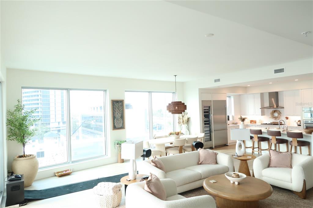 An open-concept living and dining area features floor-to-ceiling windows, white furniture, and a modern kitchen — 2910 W BARCELONA STREET UNIT 604, TAMPA, FL