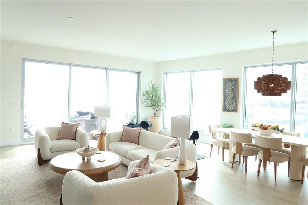 A bright, open-concept living and dining area features white furniture, light wood floors, and floor-to-ceiling windows — 2910 W BARCELONA STREET UNIT 604, TAMPA, FL