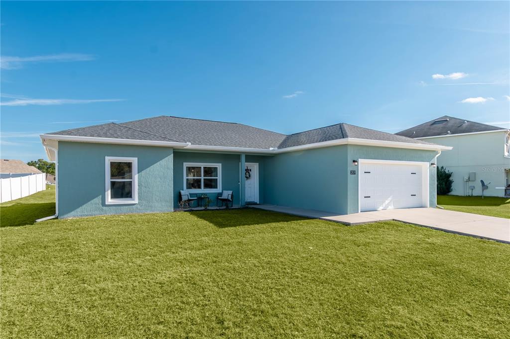 A single-story teal house with a white garage door and a front porch area — 2839 NE 43RD ROAD, OCALA, FL