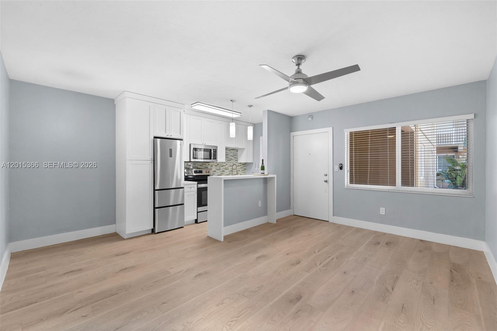 A kitchen with white cabinets and stainless steel appliances opens into a living area — 6330 SW 79th St # 4, South Miami FL 33143, SOUTH MIAMI, FL