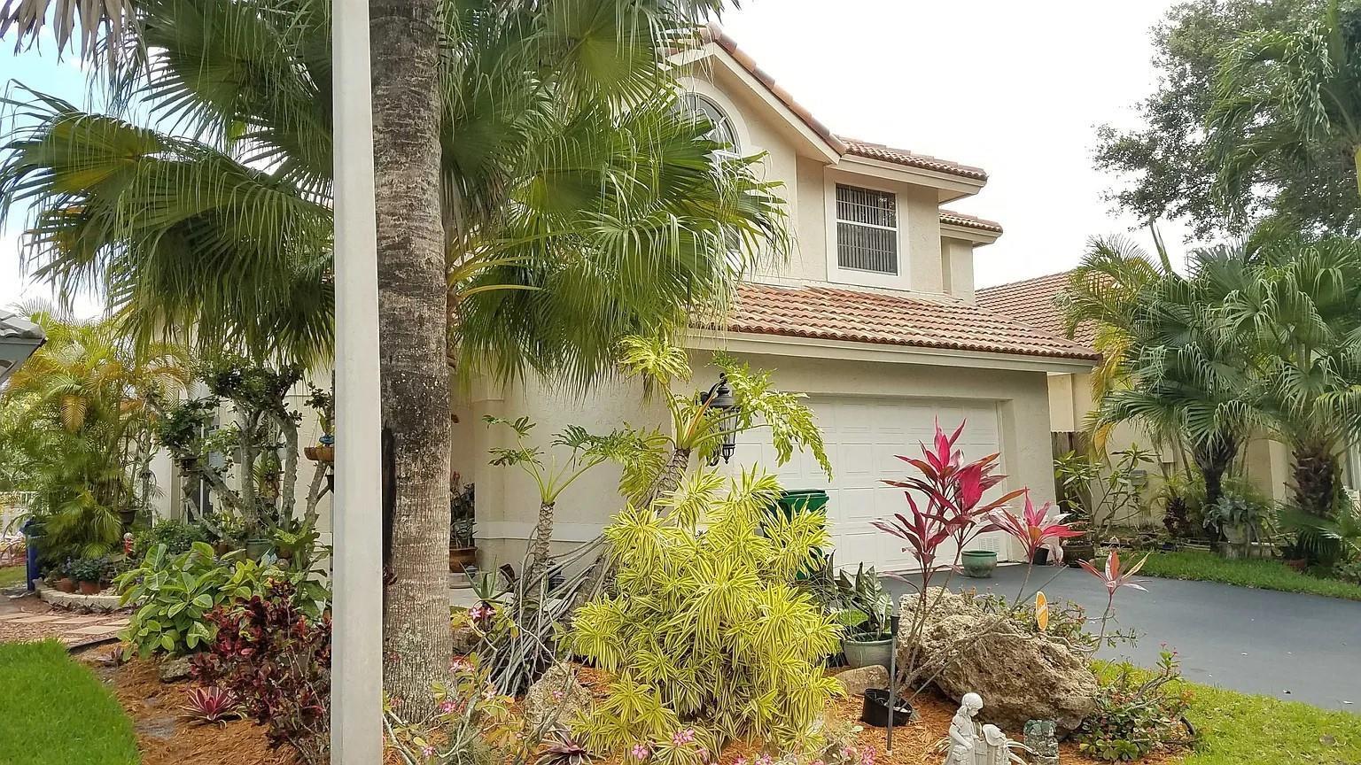 A two-story house with a tile roof, garage, and lush tropical landscaping in the front yard — 6930 NW 28th Street, Margate FL 33063, MARGATE, FL