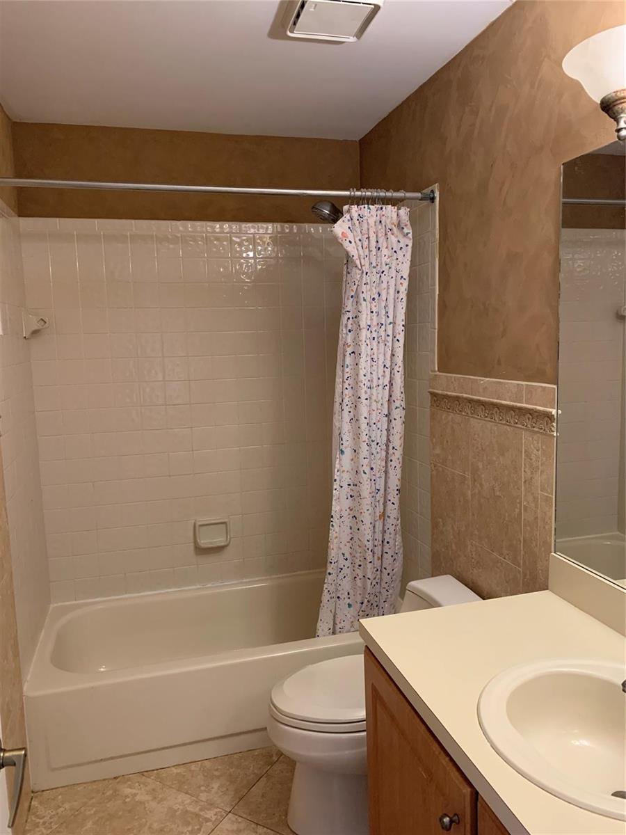A bathroom features a shower-tub combination with white tiles, a toilet, and a vanity — 6930 NW 28th Street, Margate FL 33063, MARGATE, FL