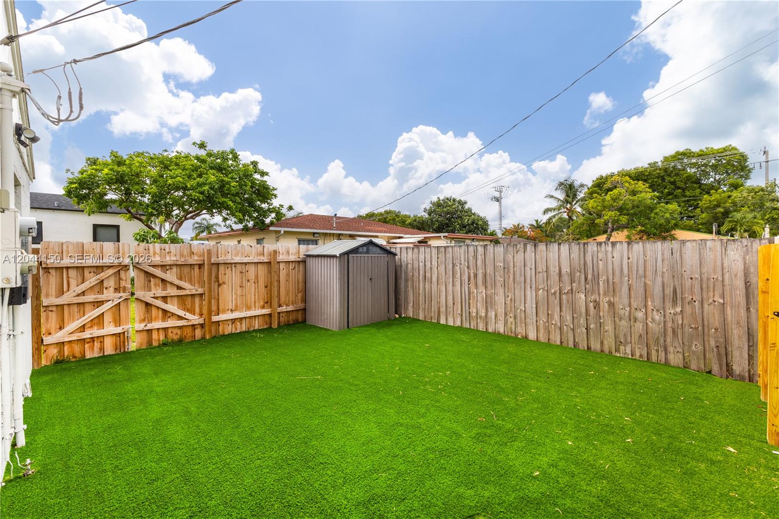 A fenced backyard features artificial turf and a small metal storage shed — 1918 Taft St, Hollywood FL 33020, HOLLYWOOD, FL
