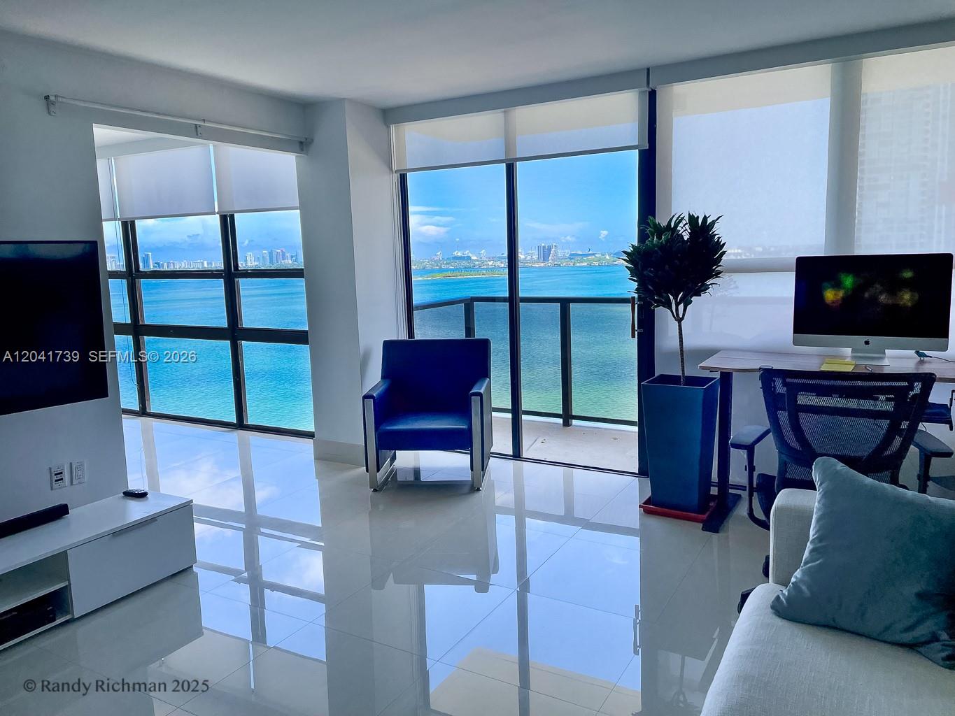 A bright living room features white tile floors, floor-to-ceiling windows, and a panoramic ocean view — 600 NE 36th St # 1820, Miami FL 33137, MIAMI, FL