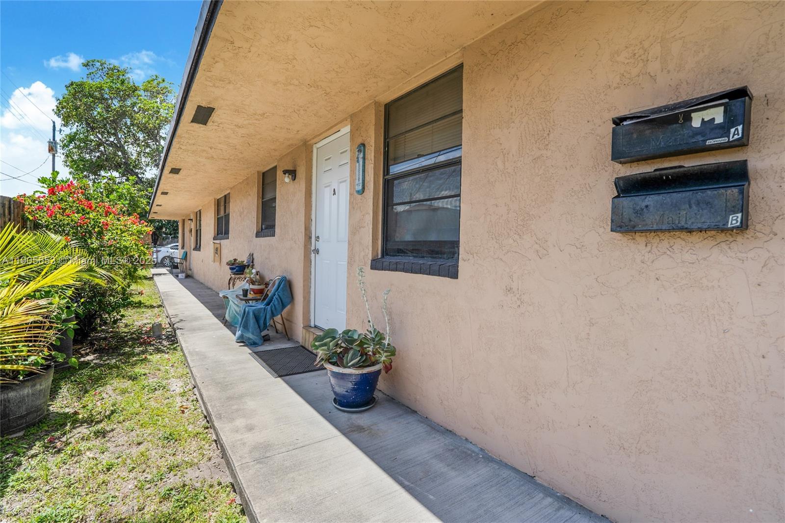 A concrete walkway runs along the exterior wall of a tan building with two mailboxes — 1734 N 16th Ct, Hollywood FL 33020, HOLLYWOOD, FL