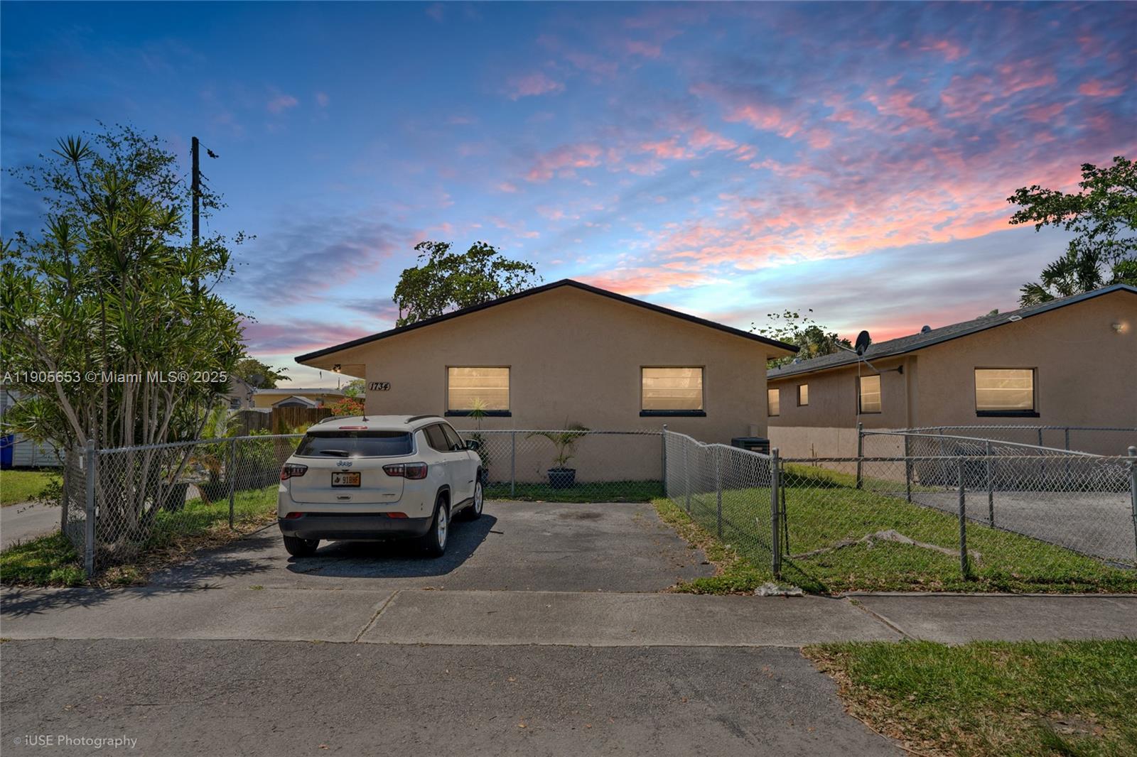 A single-story house with a white SUV parked in the driveway behind a chain-link fence — 1734 N 16th Ct, Hollywood FL 33020, HOLLYWOOD, FL