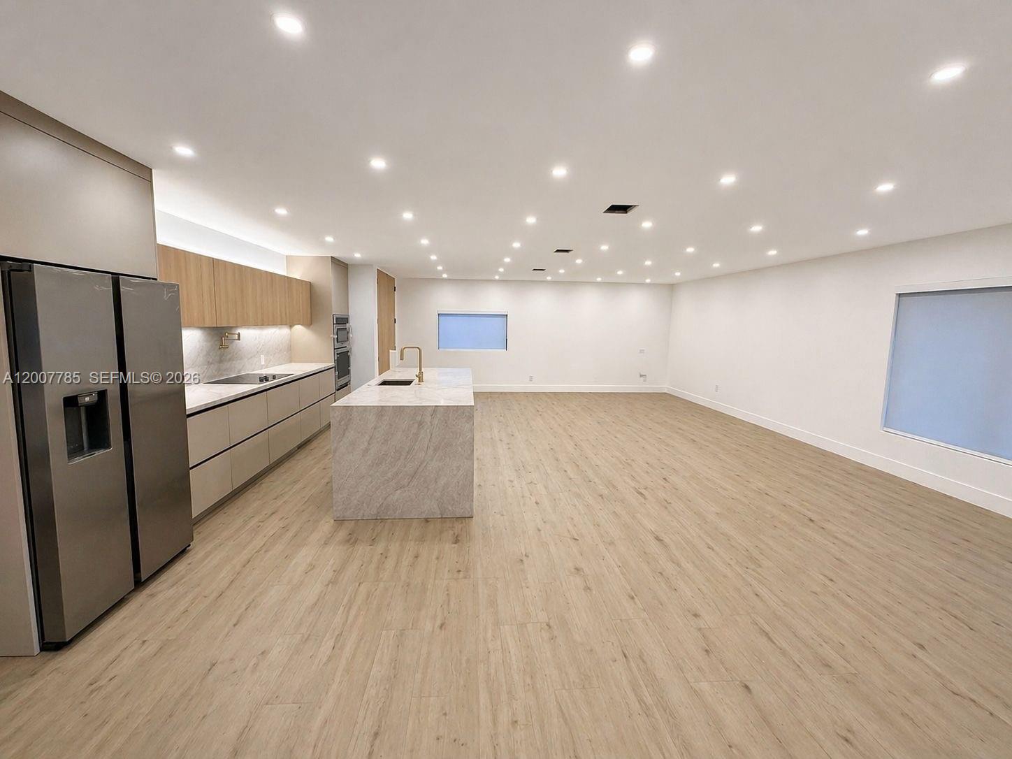 A modern kitchen features light wood cabinets, a stone island, and recessed ceiling lighting — 12810 SW 18th St, Miami FL 33175, MIAMI, FL