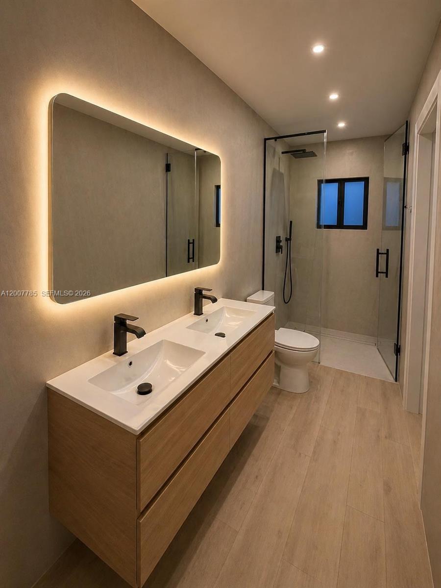 A modern bathroom features a double vanity with a backlit mirror and a glass shower — 12810 SW 18th St, Miami FL 33175, MIAMI, FL