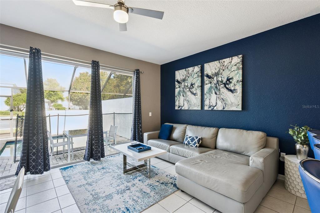 A living room features a grey sectional sofa, a blue accent wall, and sliding glass doors — 2530 MANESHAW LANE, KISSIMMEE, FL