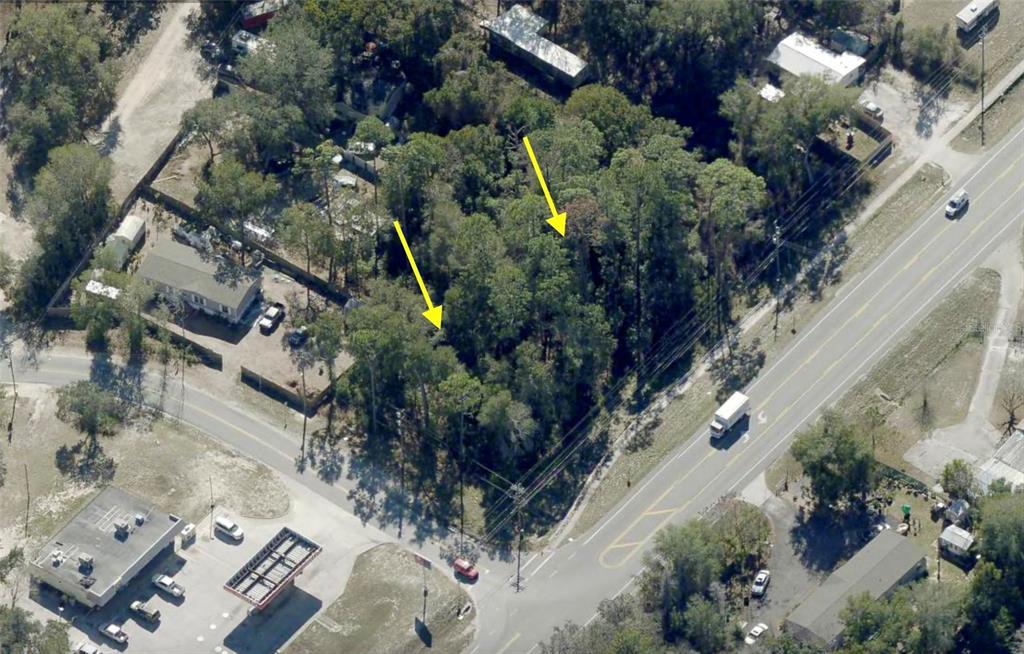 An aerial view shows a wooded, undeveloped lot bordered by a road and nearby buildings — LOT 14 STATE ROAD 44, EUSTIS, FL