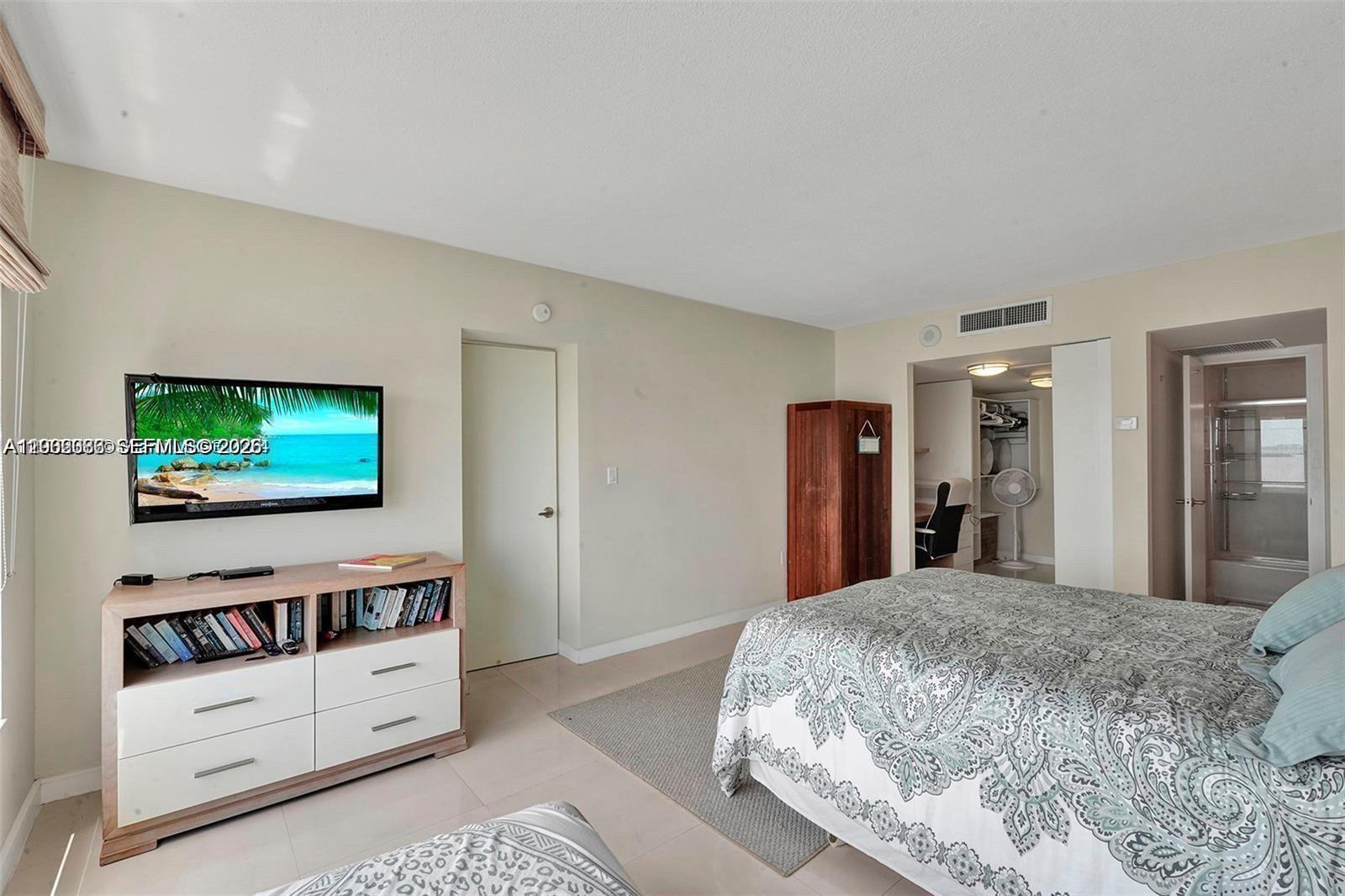 A bedroom features a bed, a television mounted above a dresser, and an open closet — 11111 Biscayne Blvd # 18E, Miami FL 33181, MIAMI, FL