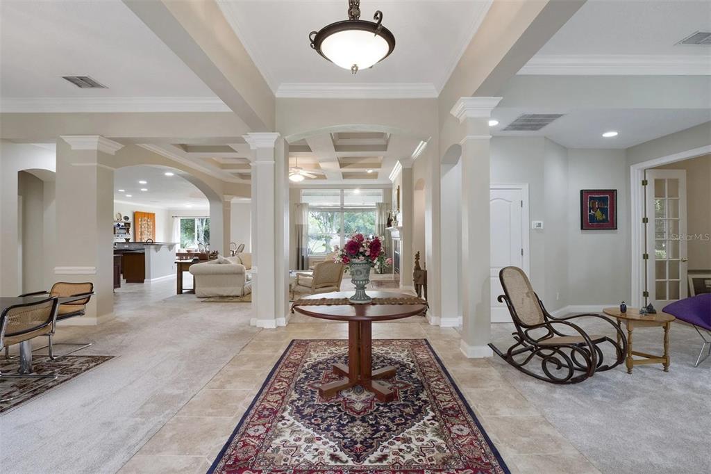 A spacious foyer features a central round table, a patterned rug, and arched room transitions — 25551 HAWKS RUN LANE, SORRENTO, FL