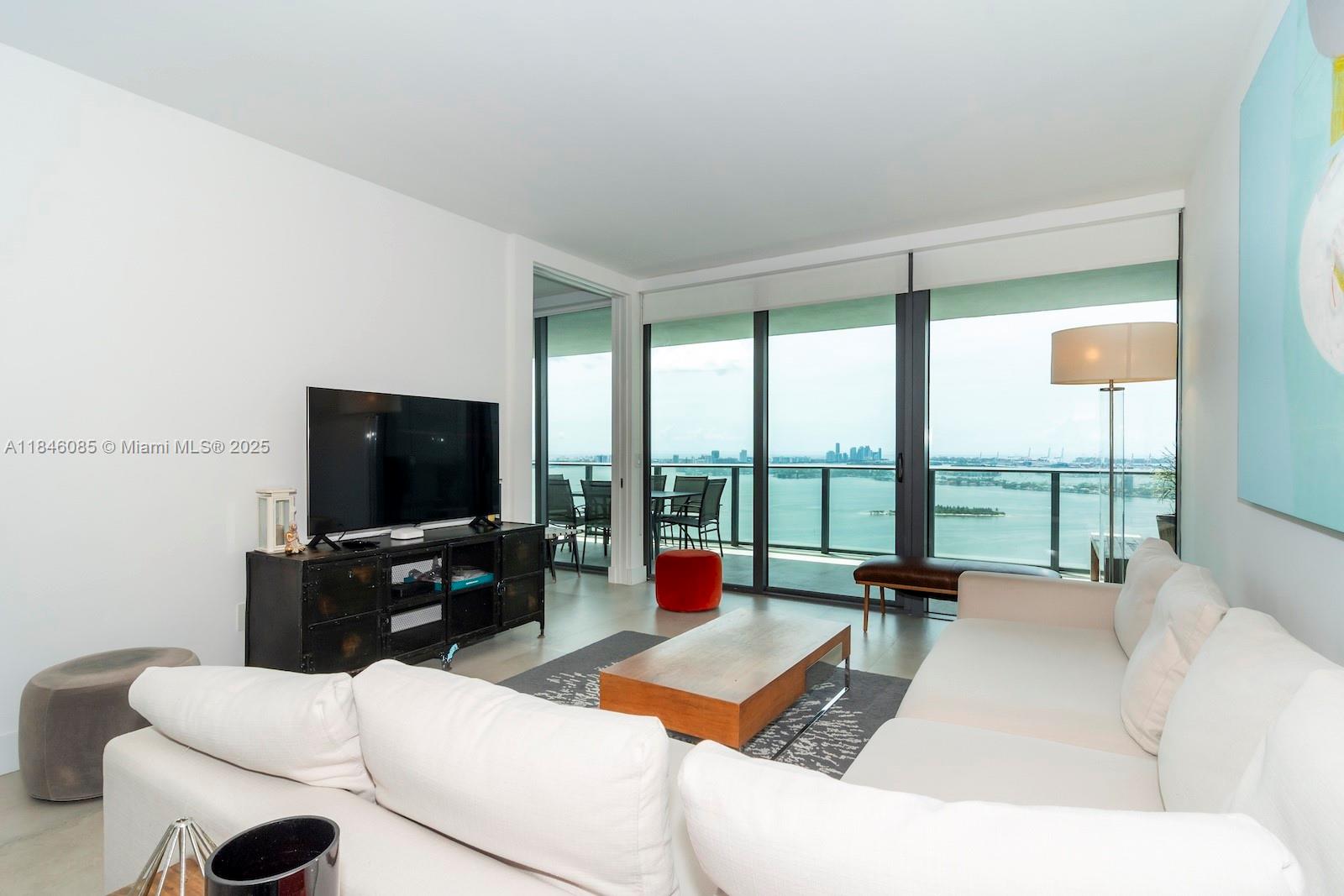 A living room features a white sofa, a wooden coffee table, and floor-to-ceiling windows — 650 NE 32nd St # 4206, Miami FL 33137, MIAMI, FL