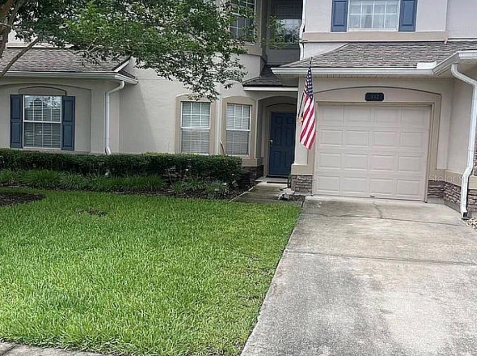 A two-story townhouse features a beige exterior, a single-car garage, and a front lawn — 332 WOODED CROSSING CIRCLE, ST AUGUSTINE, FL