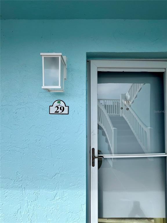 A light blue exterior wall features a white light fixture and a door marked 29 — 199 WAKULLA LANE UNIT 29, COCOA BEACH, FL