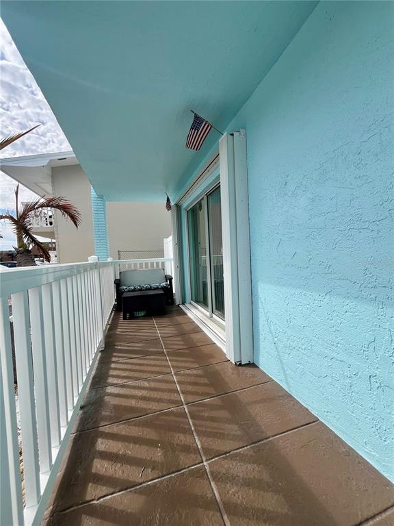 A covered balcony with brown tiled flooring, a white railing, and a light blue wall — 199 WAKULLA LANE UNIT 29, COCOA BEACH, FL