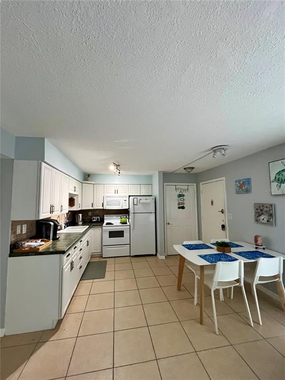 A kitchen with white cabinets, tile flooring, and a dining table with four chairs — 199 WAKULLA LANE UNIT 29, COCOA BEACH, FL