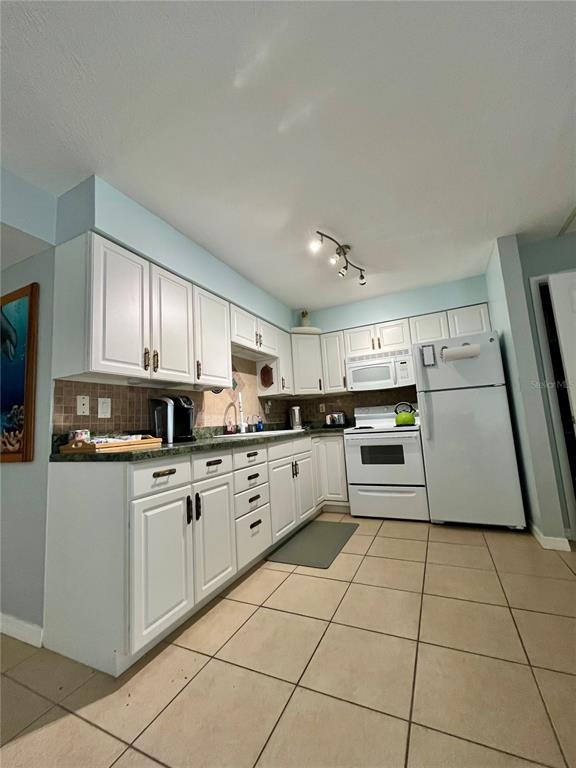 A kitchen features white cabinets, a white refrigerator, a white stove, and tiled floors — 199 WAKULLA LANE UNIT 29, COCOA BEACH, FL