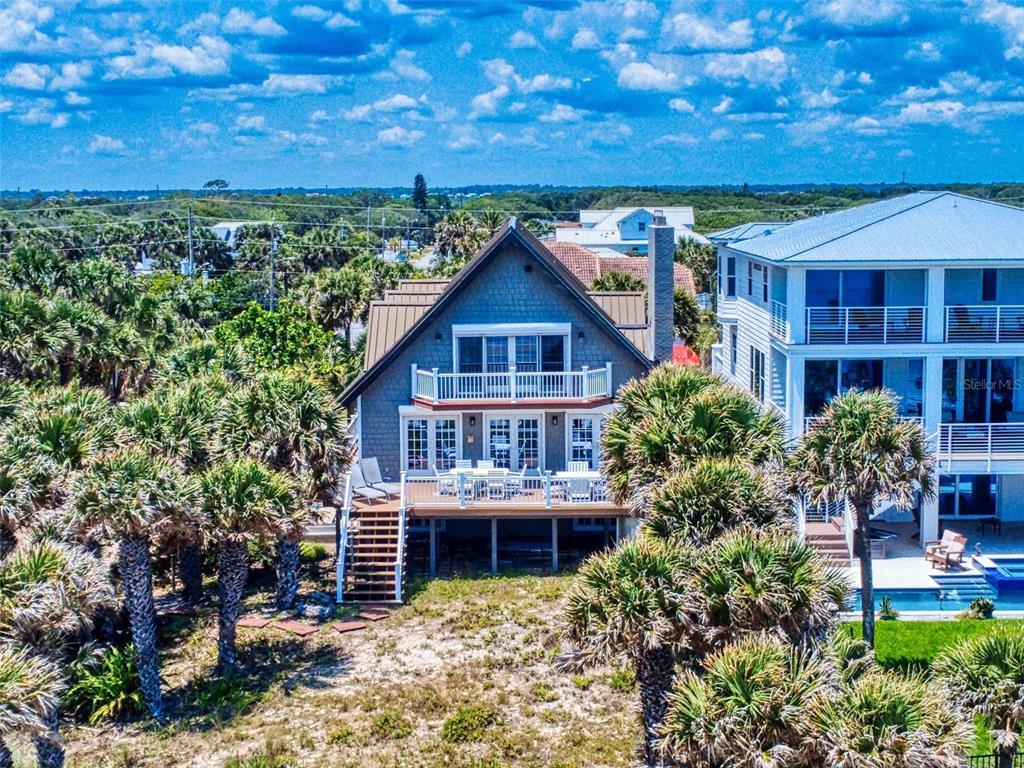 An elevated coastal house with a wooden deck, stairs, and a balcony surrounded by palm trees — 1913 HILL STREET UNIT 2, NEW SMYRNA BEACH, FL
