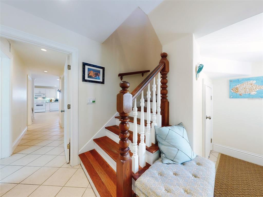 A wooden staircase with white balusters sits beside a doorway leading to a kitchen — 1913 HILL STREET UNIT 2, NEW SMYRNA BEACH, FL