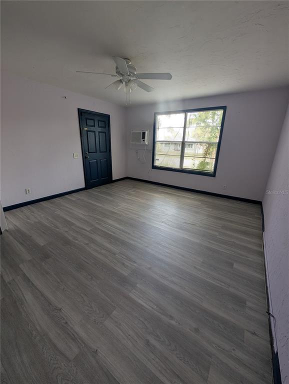 An empty room with light wood-look flooring, a ceiling fan, a window, and a door — 2004 2ND AVENUE E UNIT 1, BRADENTON, FL