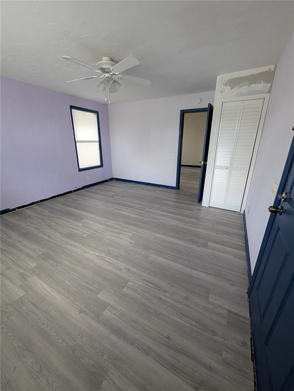An empty bedroom features light purple walls, gray wood-look flooring, and a white ceiling fan — 2004 2ND AVENUE E UNIT 1, BRADENTON, FL