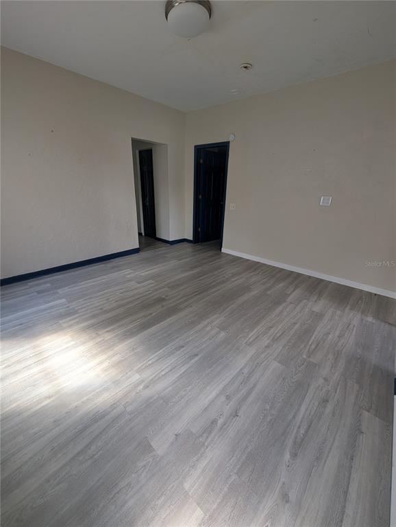 An empty room features light-colored wood-look flooring, beige walls, and two dark-colored doorways — 2004 2ND AVENUE E UNIT 1, BRADENTON, FL