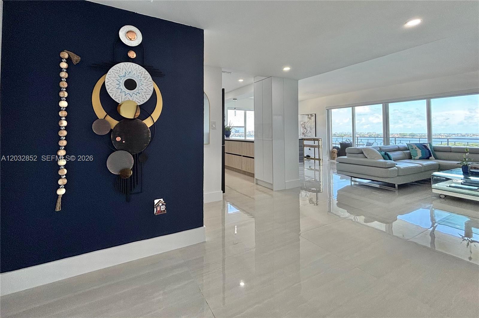 A modern living area features a navy accent wall, large tile flooring, and floor-to-ceiling windows — 11111 NE Biscayne Blvd # 16A, Miami FL 33181, MIAMI, FL