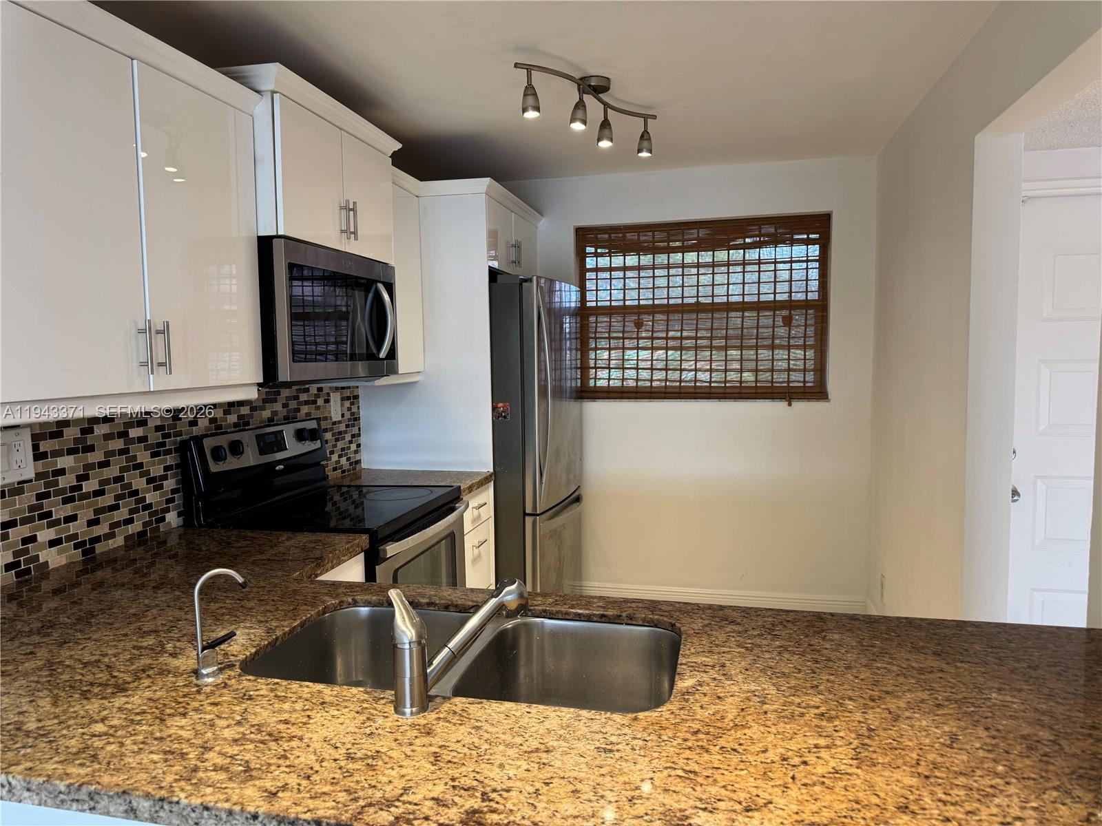 A kitchen features white cabinets, granite countertops, stainless steel appliances, and a double sink — 1831 Sabal Palm Dr # 403, Davie FL 33324, DAVIE, FL