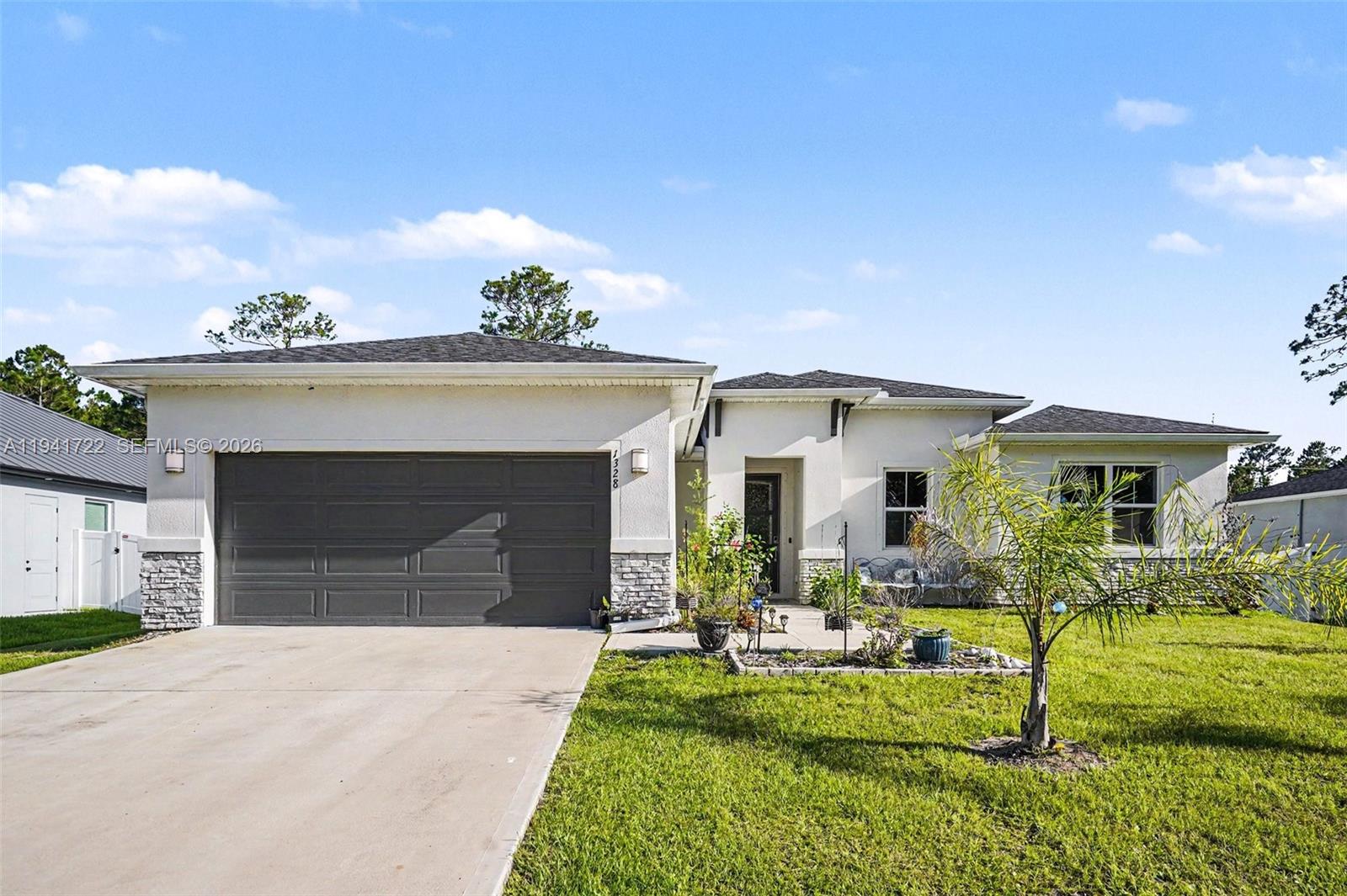 A single-story house with a white stucco exterior, stone accents, and a two-car garage — 1328 Washburn ST SE, Palm Bay FL 32909, PALM BAY, FL