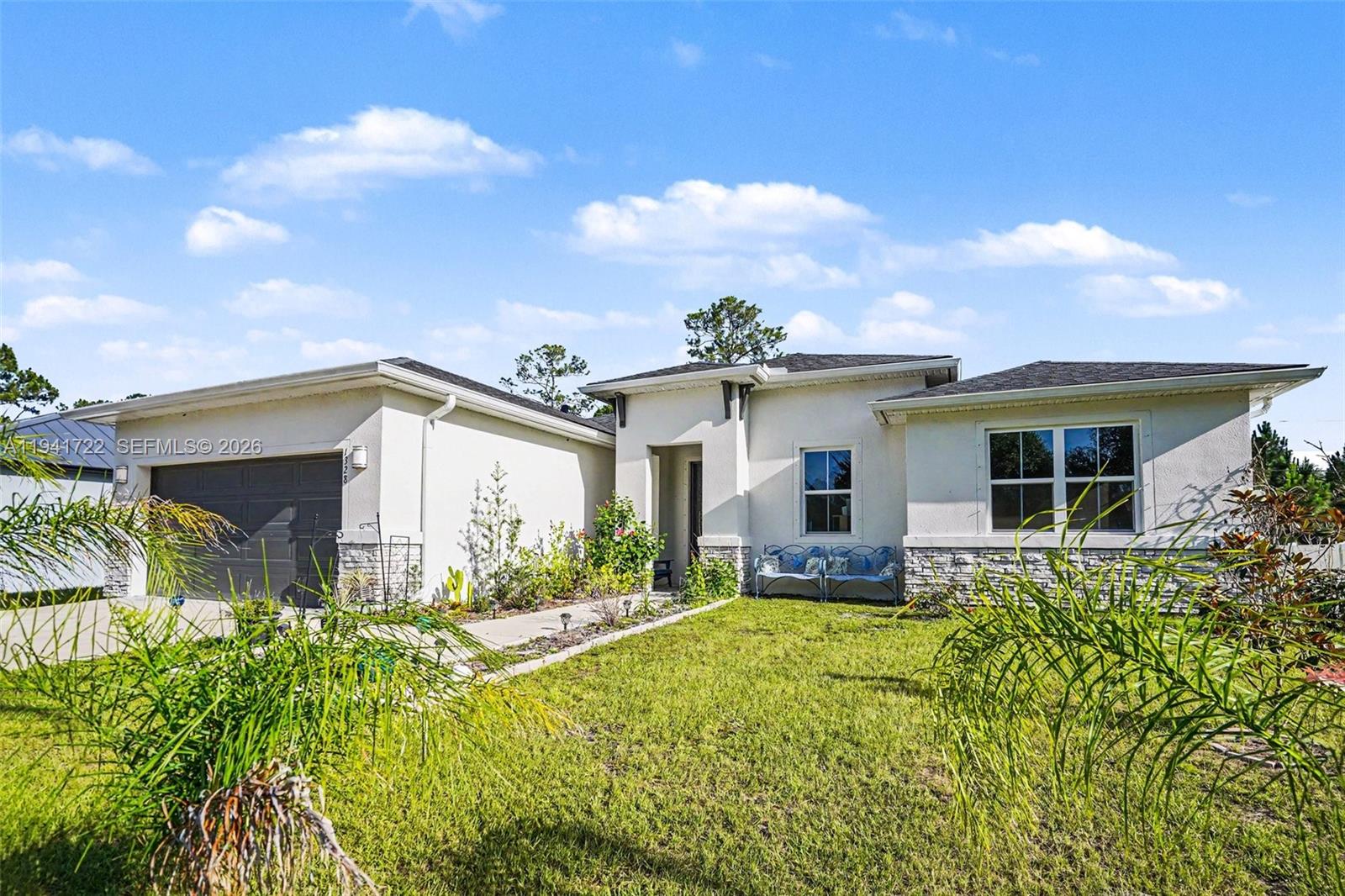 A single-story house with a garage, stone accents, and a front lawn under a blue sky — 1328 Washburn ST SE, Palm Bay FL 32909, PALM BAY, FL