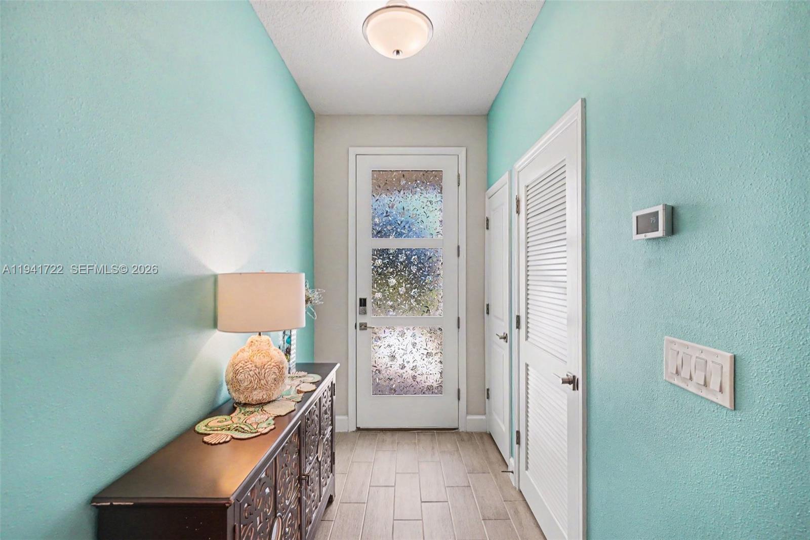 A hallway features light blue walls, a dark wood console table, and a glass-paneled door — 1328 Washburn ST SE, Palm Bay FL 32909, PALM BAY, FL