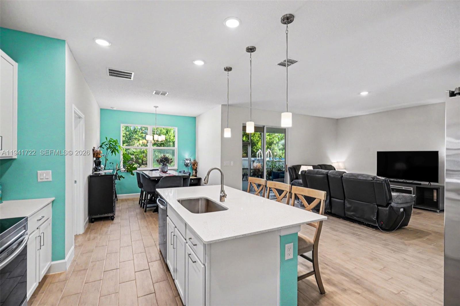 A kitchen with a white island and quartz countertops opens into a living and dining area — 1328 Washburn ST SE, Palm Bay FL 32909, PALM BAY, FL