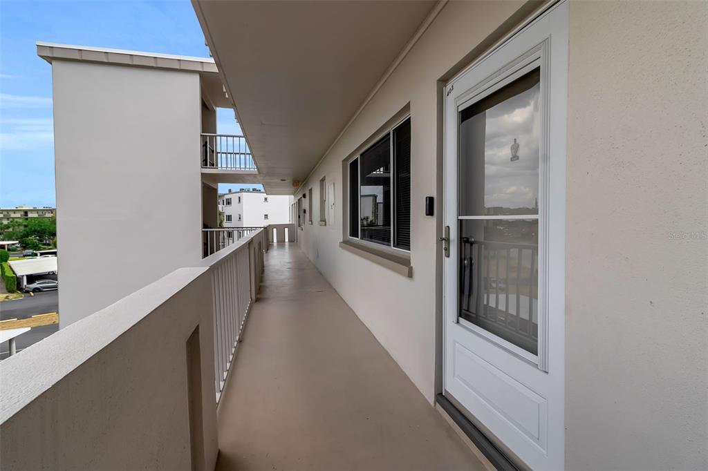 An exterior walkway with a white railing leads to a door of a residential unit — 4210 IRONWOOD CIRCLE UNIT 403J, BRADENTON, FL