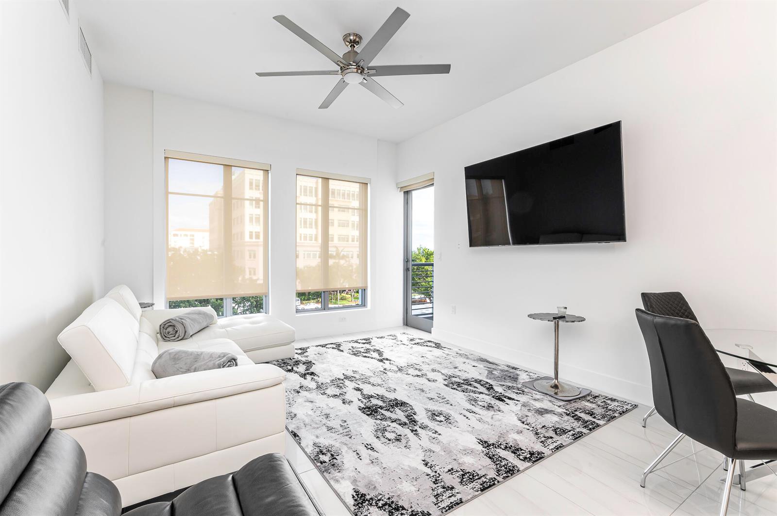 A living room features a white sectional sofa, a patterned rug, and a wall-mounted television — 155 E Boca Raton Road # 415, Boca Raton FL 33432, BOCA RATON, FL