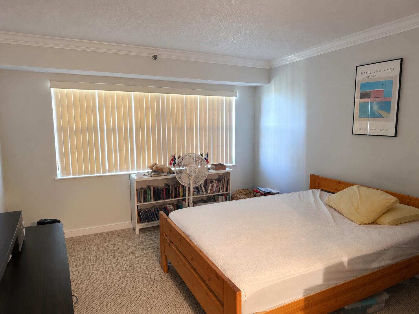A bedroom features a wooden bed frame, a bookshelf under a window, and beige carpeting — 2900 N Course Drive # 1005, Pompano Beach FL 33069, POMPANO BEACH, FL