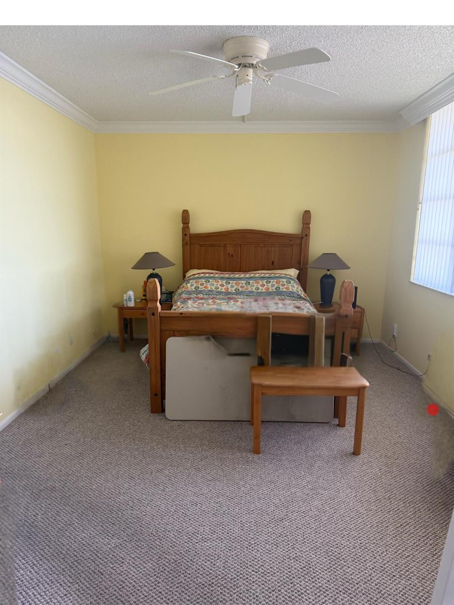 A bedroom with yellow walls, a wooden bed frame, and a ceiling fan — 2900 N Course Drive # 1005, Pompano Beach FL 33069, POMPANO BEACH, FL