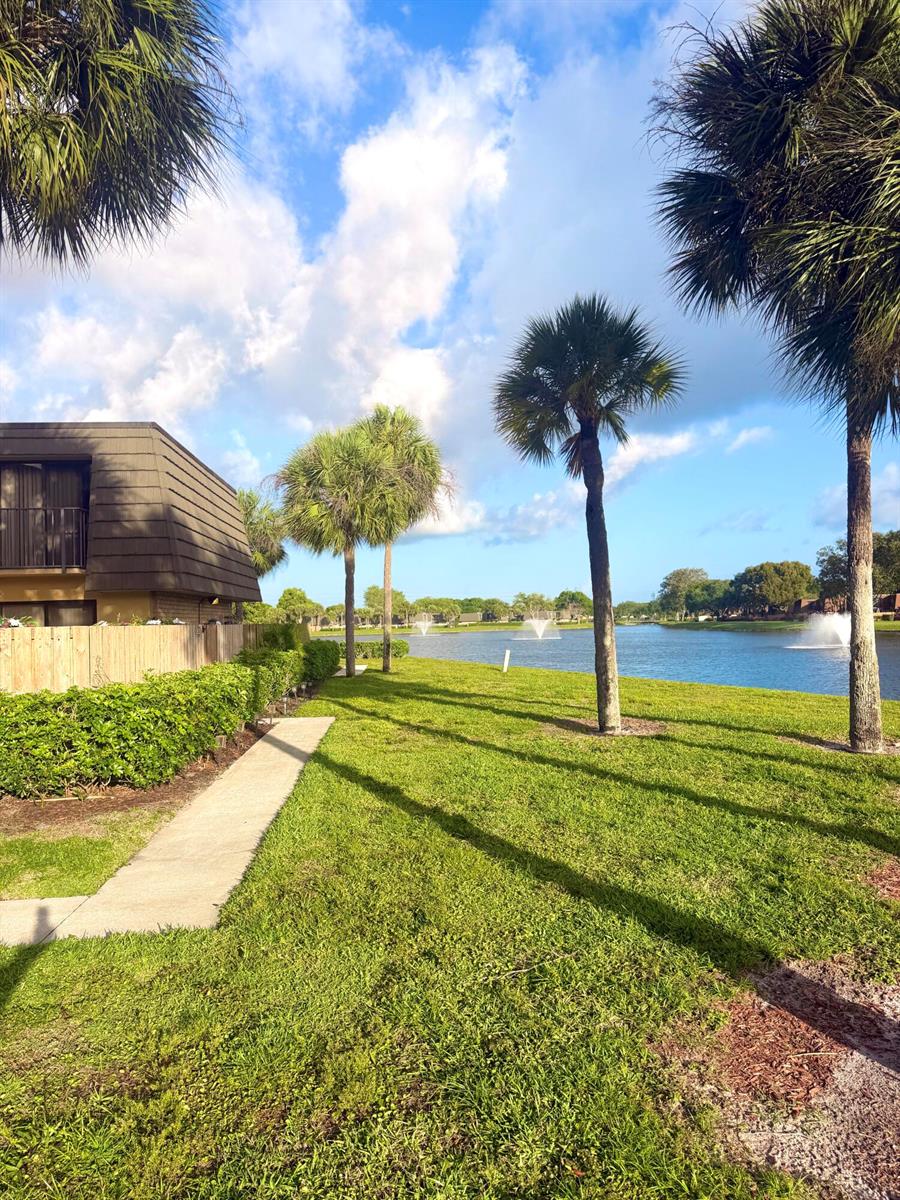 A view of a grassy lawn, palm trees, and a lake with fountains behind a building — 812 8th Way, West Palm Beach FL 33407, WEST PALM BEACH, FL