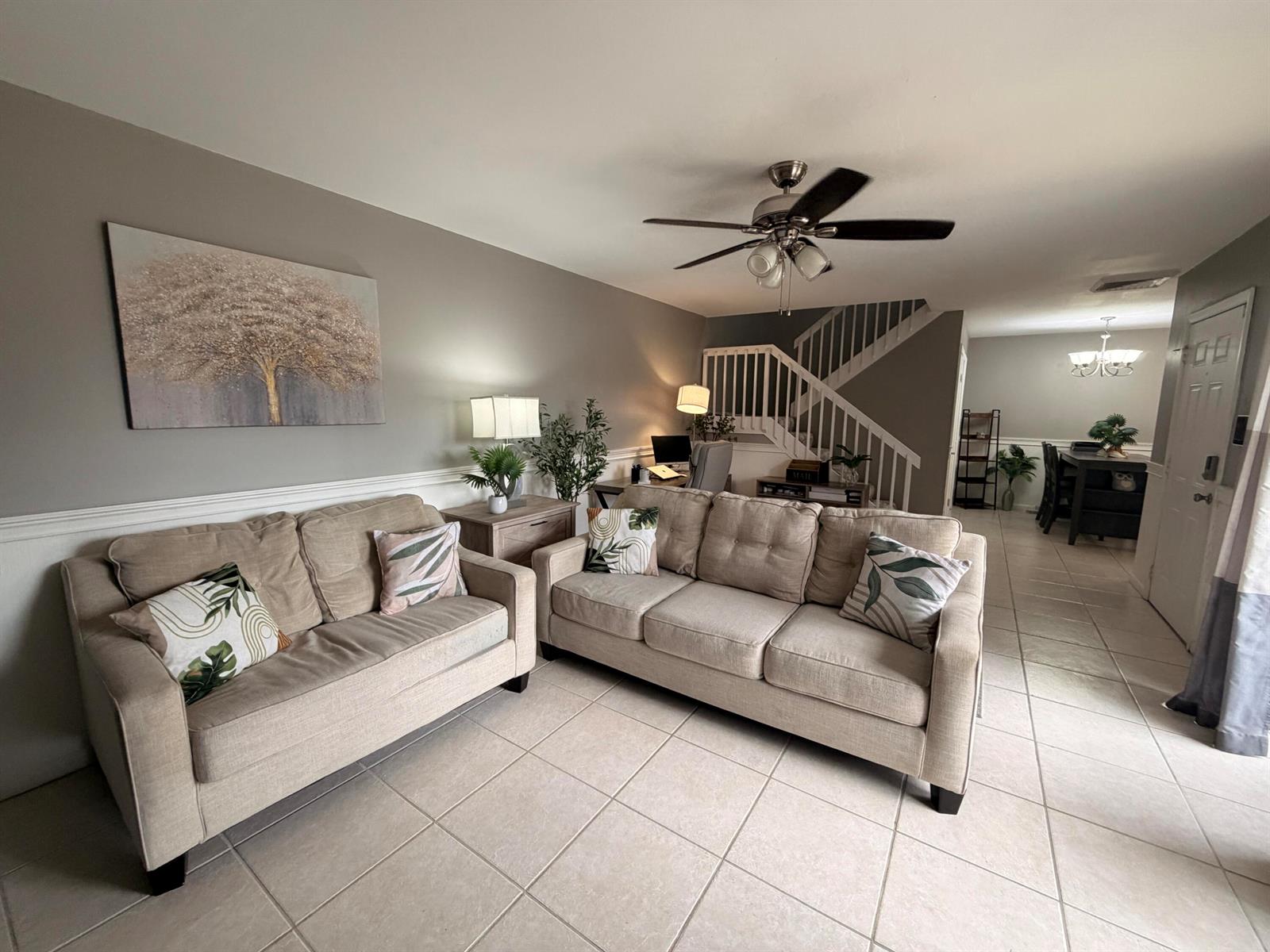 A living room features two beige sofas, a ceiling fan, and stairs leading to another level — 812 8th Way, West Palm Beach FL 33407, WEST PALM BEACH, FL