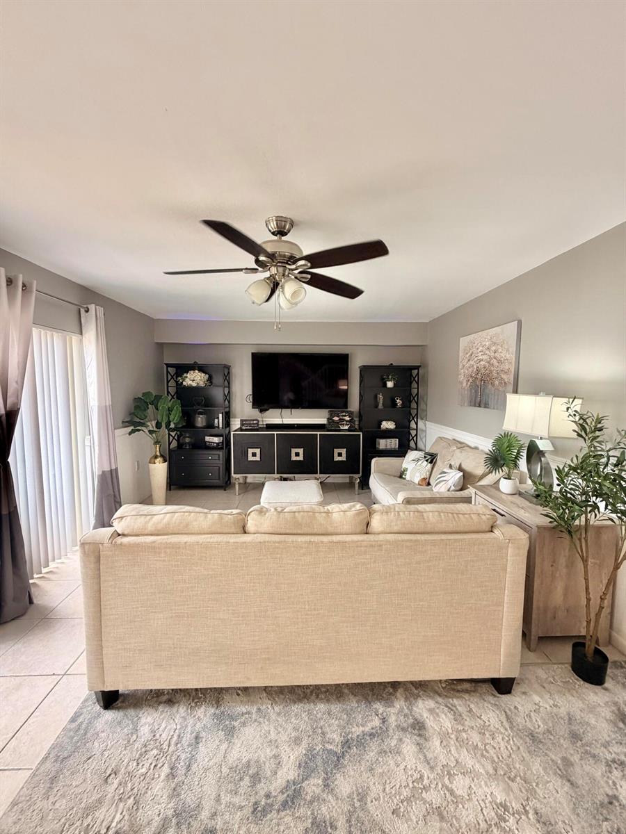 A living room features a beige sofa, a television on a console, and two black bookshelves — 812 8th Way, West Palm Beach FL 33407, WEST PALM BEACH, FL
