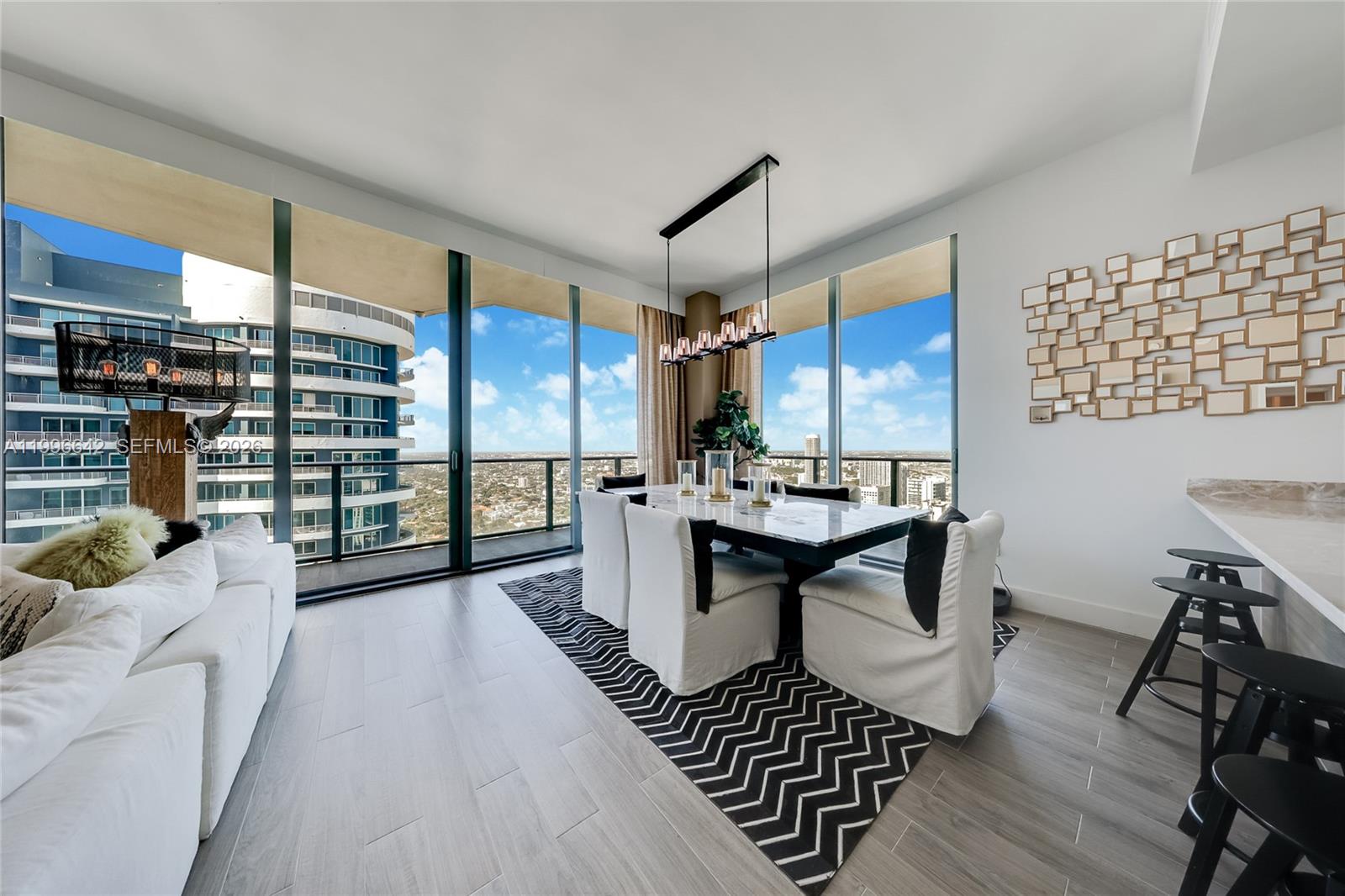 A modern dining area features a marble table, white slipcovered chairs, and floor-to-ceiling windows — 1300 S Miami Ave, Miami FL 33130, MIAMI, FL