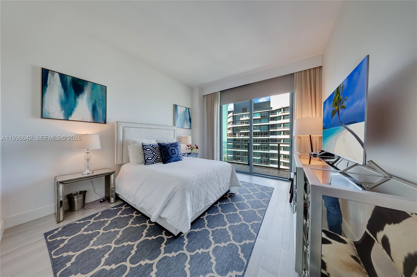 A modern bedroom features a bed, mirrored furniture, a patterned rug, and a balcony view — 1300 S Miami Ave, Miami FL 33130, MIAMI, FL