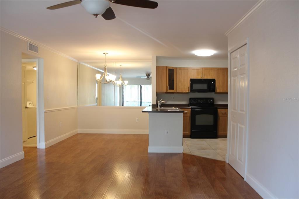 An open-concept living area features wood flooring, a kitchen with light cabinets, and a mirror — 5602 BAYWATER DRIVE, TAMPA, FL