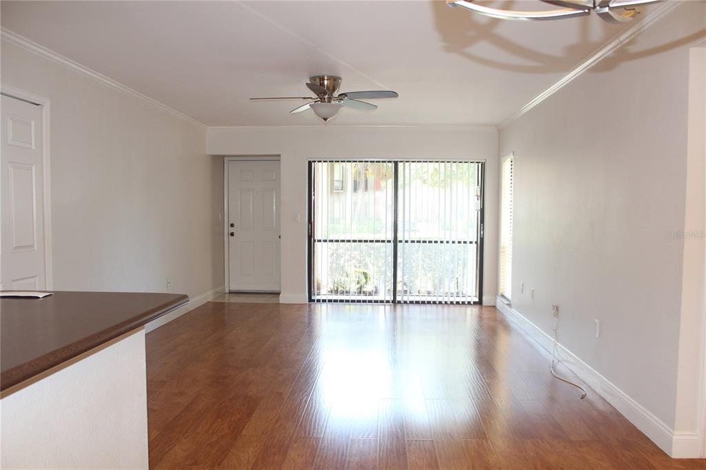 An open living area features wood-look flooring, a ceiling fan, and sliding glass patio doors — 5602 BAYWATER DRIVE, TAMPA, FL