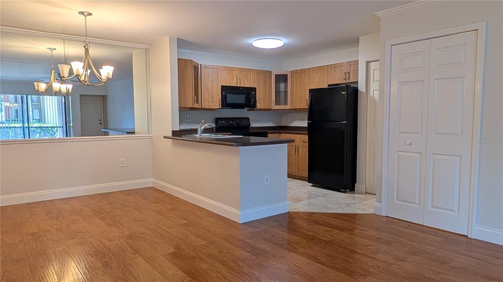 A kitchen with light wood cabinets, black appliances, and a breakfast bar overlooks a dining area — 5602 BAYWATER DRIVE, TAMPA, FL