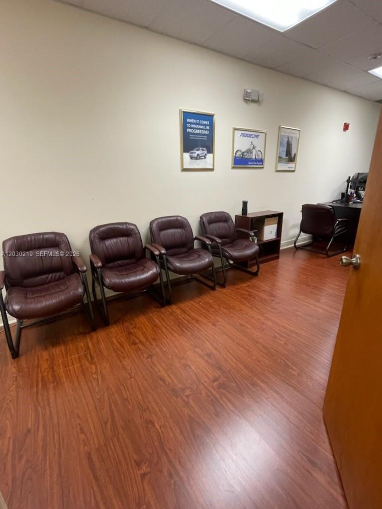 A small office space features four brown leather chairs, wood-look flooring, and wall-mounted Progressive advertisements — 12900 SW 128th St # 104, Miami FL 33186, MIAMI, FL