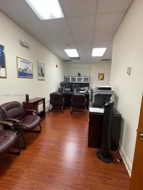 An office with wood-look flooring, two guest chairs, a desk, and a printer — 12900 SW 128th St # 104, Miami FL 33186, MIAMI, FL